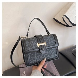 Close-up of black retro handbag with letter print and large golden H-shaped buckle