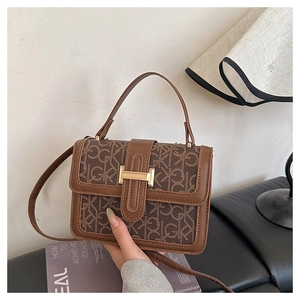 Detail of vintage GK monogram pattern on brown crossbody bag with gold metal buckle