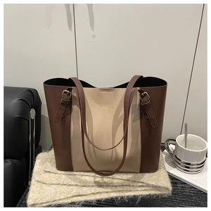 Close-up of contrast color tote bag with gold logo and adjustable buckled straps