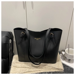 Detail of black faux leather tote bag with yellow Tidal Dryness Bags print and gold buckles