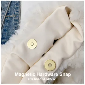 Macro shot of dual light gold magnetic buckles and cream leather on faux fur bag