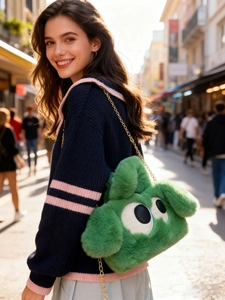 Détail du sac monstre en peluche verte avec de grands yeux et une chaîne dorée
