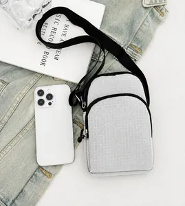 Detail view of the gray fabric crossbody phone bag with multi-layer zipper and nylon strap