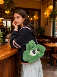 Détail du sac bandoulière en peluche verte avec de grands yeux et chaîne dorée