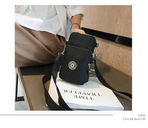 Detail of a black nylon sports phone bag with double zippers and adjustable strap