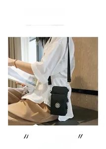 Black mini crossbody phone bag with adjustable strap shown on model for size scale