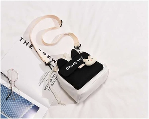 Detalle del bolso bandolera de lona con orejas de conejo 3D y colgante de peluche suave