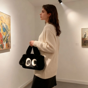 Détail d'un sac à main noir en peluche avec grands yeux brodés et chaîne dorée