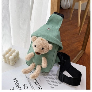 Detalle del bolso bandolera de lona verde claro con un oso de peluche 3D y correa ajustable