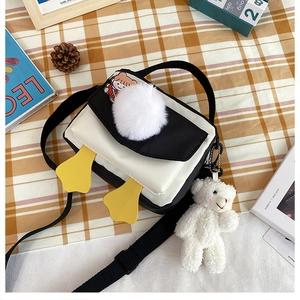 Dettaglio borsa a tracolla in tela con toppa a cartone e pompon bianco decorativo