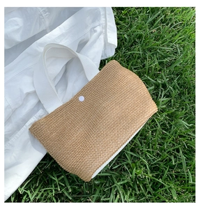 Detail of hand-woven straw beach bag with white canvas handles and snap button