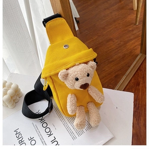 Detalle del bolso de lona amarillo con un oso de peluche 3D y correa negra ajustable