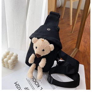 Detail of a black canvas crossbody bag with a 3D plush teddy bear and adjustable strap