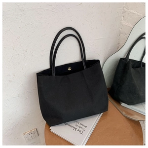 Détail d'un sac cabas en toile noire minimaliste avec fermeture à bouton aimanté doré