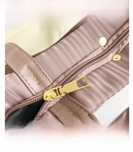 Detail of smooth gold zipper on a pink quilted tote bag with dark fabric lining