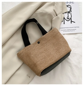 Macro view of woven straw beach bag with contrast black faux leather bottom and button closure
