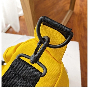 Detail of matte black metal hardware and woven strap on a yellow canvas bag