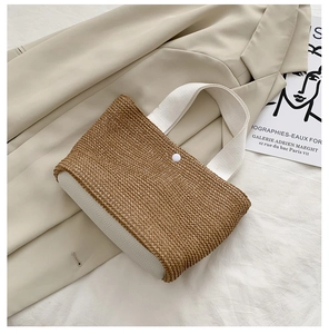 Detail of straw woven tote bag with white leather straps and button on beige blazer
