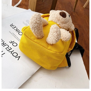 Detalle de bandolera de lona amarilla con osito de peluche y cierre de cremallera