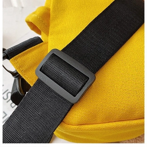 Detail of yellow canvas bag featuring adjustable black nylon strap and matte plastic buckle