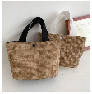 Detail of woven straw beach bags showing natural textures and contrast fabric handles