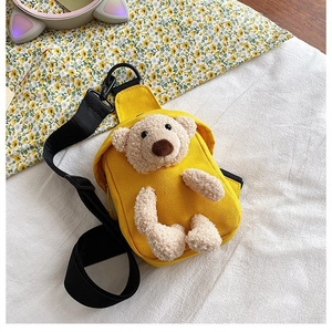 Detailed close-up of a bright yellow canvas bag featuring a 3D plush teddy bear mascot