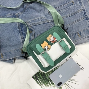Détail du sac bandoulière en toile avec rabat vert et écussons mignons d'ours