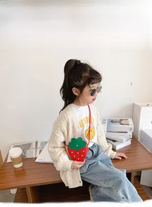 Close-up of a red strawberry shaped crossbody bag for girls with green leaf details