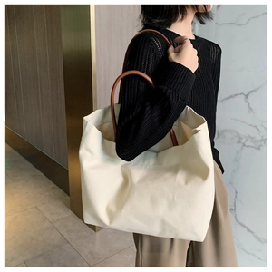 Vue détaillée du grand sac cabas en toile crème avec des anses en cuir marron au porté