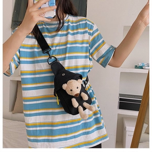 Mirror selfie showing the black canvas crossbody bag with a plush teddy bear ornament