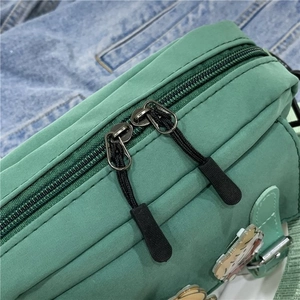 Détail du sac en toile vert menthe montrant la double fermeture éclair et la texture