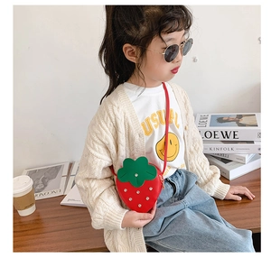 Close-up of strawberry-shaped red crossbody bag with leaf lid on little girl