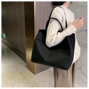 Vue latérale d'un grand sac fourre-tout en toile noire porté par un mannequin