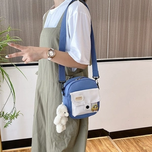 Cute blue canvas crossbody bag with white pocket and plush bear charm for casual wear