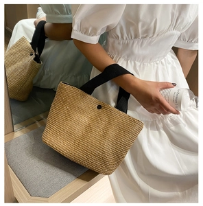 Detailed weave texture of summer straw beach bag with contrasting black handle and button