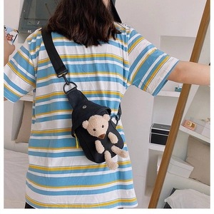 Detalle de riñonera de lona negra para mujer con un accesorio decorativo de oso de peluche