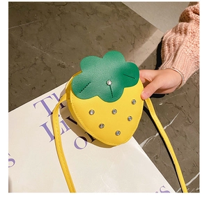 Close-up of yellow strawberry kids crossbody bag with leaf lid and sparkling sequins
