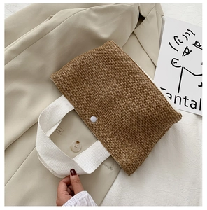 Detail of woven straw handbag texture with white canvas handles and snap button closure