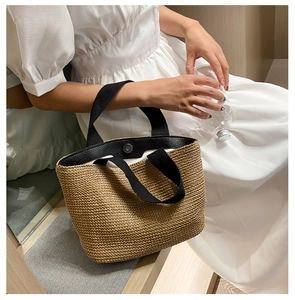 Detail showing natural straw texture with contrast black strap and magnetic clasp