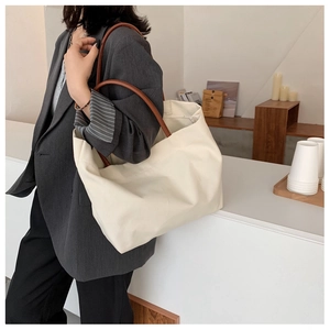 Grand sac cabas minimaliste en toile crème avec anses en cuir marron dans un café chic
