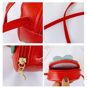 Detail view of red strawberry-shaped PU leather bag with metal zipper and strap stitching