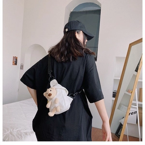 Detalle de bolso bandolera de lona blanca con osito de peluche 3D y correa ajustable negra