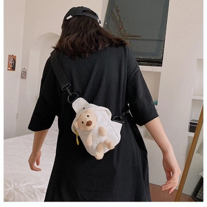Detail of white canvas crossbody bag featuring a 3D plush bear and black adjustable strap