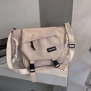 Detail view of beige nylon messenger bag with buckle closure and fashion label