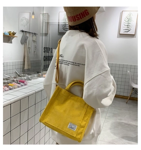Vista posteriore di una modella con borsa tote in velluto a coste giallo trendy