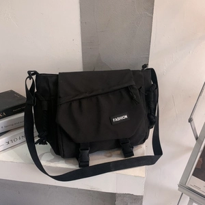 Close-up of black crossbody messenger bag with buckle closure and fashion label