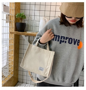 Dettaglio di una borsa tote in velluto a coste bianco sporco con etichetta blu e tracolla