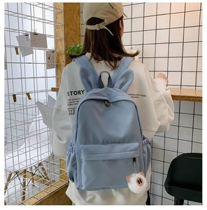 Détail d'un sac à dos bleu clair avec oreilles de lapin et peluche sur un mannequin