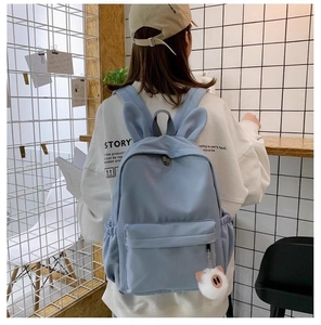 Détail d'un sac à dos scolaire bleu clair avec oreilles de lapin et peluche sur un modèle