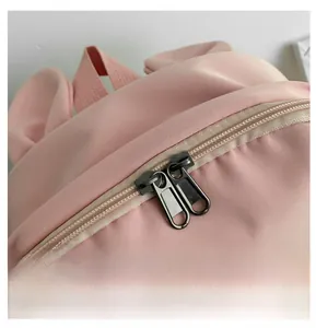 Détail d'un sac à dos rose avec fermetures éclair en métal noir et tissu de qualité